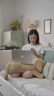 年轻女人在家使用电脑和手机