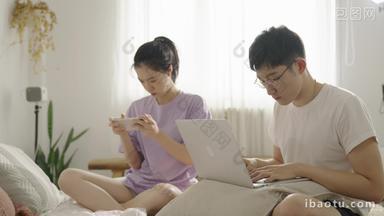 年轻情侣在家使用手机和电脑