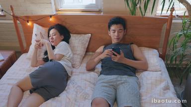 青年情侣<strong>躺</strong>在床上各自玩手机