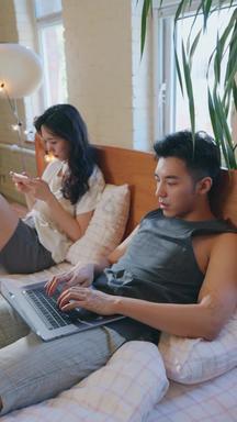 <strong>青年</strong>情侣坐在床上各自玩手机