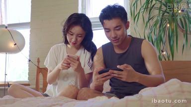 青年情侣坐在床上玩手机