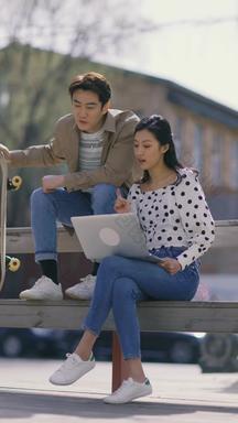 快乐商务情侣在户外使用笔记本电脑