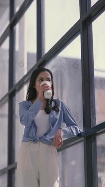 倚在窗边喝奶茶的白领一次性杯子4K分辨率实拍素材