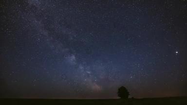 夏天的草地上，夜空中的银河在孤零零的树上。明亮的<strong>星</strong>辰和<strong>流星</strong>在风景之上的轨<strong>迹</strong>。欧洲的观点