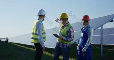 工人们在一排排长排的太阳能电池板之间交谈