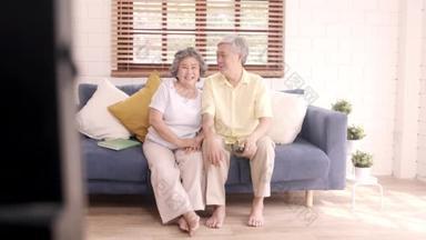 在家里客厅里看电视的一对亚洲老<strong>夫妻</strong>，在家里放松的时候，躺在沙发上享受爱情的时刻。享受家庭幸福的<strong>生活方式</strong>.