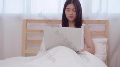 年轻的商业自由职业亚洲妇女工作在笔记本电脑检查社交媒体，而躺在床上，当放松在卧室在<strong>家里</strong>。生活方式 女性在房子的概念.