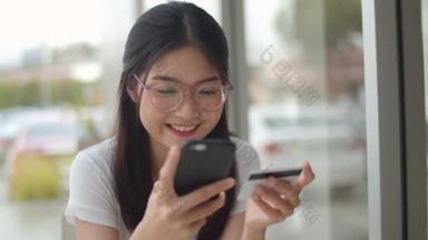 自由职业者亚洲女性在咖啡店网上购物。年轻的亚洲女孩使用手机，信用卡购买和购买电子<strong>商务</strong>互联网在户外咖啡厅的餐桌上在晚上的概念。慢动作.