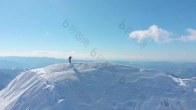 空中: 壮观的阳光明媚的山脉环绕着一个无法辨认的滑雪者, 在滑雪前, 在覆盖山坡的新鲜粉末雪中滑雪, 拍摄到雄伟的大自然。美丽的冬季景观.