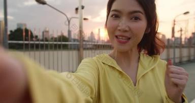 有魅力的年轻亚洲运动员在城市锻炼的同时，通过社交媒体在网上直播视频，影响了节目主持人女士。早上穿运动服在街上的女运动员.