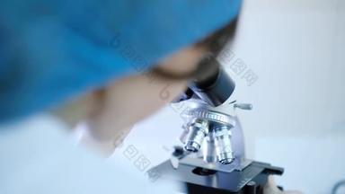 实验室助理拿着实验室显微镜坐在他的工作场所