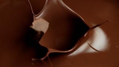 飞溅成融化巧克力的生巧克力片的超级慢动作.