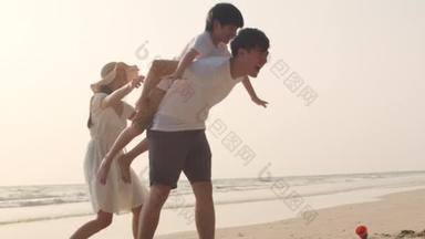 亚洲年轻快乐的家庭晚上在海滩度假.爸爸，妈妈和孩子在日落时一起在海边玩，放松点。生活方式旅行度假暑假的概念.4k慢动作.