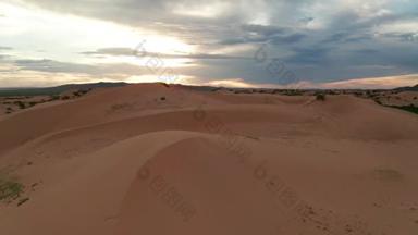 落日笼罩在沙漠的沙丘上