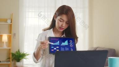 亚洲女商人在客厅工作时，用笔记本电脑和平板电脑向同事们介绍了视频通话的计划。自我隔离、社会<strong>疏离</strong>、验尸官检疫.