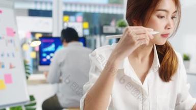成功的亚洲执行董事年轻女商人智能休闲装的绘制、书写和使用带有数字平板电脑思维的钢笔在现代总公司的工作过程中寻找灵感.