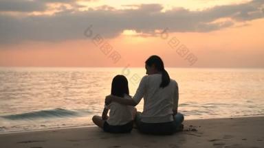 假期的概念。 母亲和女儿正在海滩上观看日落. 4k分辨率.