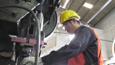 亚洲工人在金属板制造厂生产线上操作冲压机，穿着安全玻璃制服和安全帽。夜间大灯，以确保良好的外观检查质量