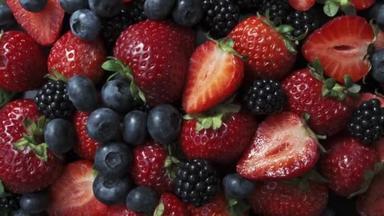 黑色背景的野生森林浆果，草莓、蓝莓和黑莓的集合.
