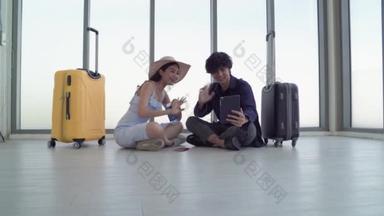 一对夫妇坐在旅客休息室的地板上，一边等着他们的航班，一边聊着天.