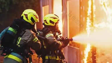 两名消防员在夜间用软管喷射房屋，扑灭火警.