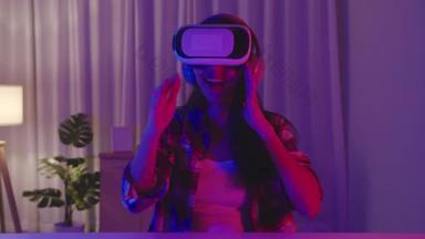 亚洲女人穿着VR游戏耳机，有着有趣的体验，可穿戴虚拟增强型现实数码创新科技快乐时刻霓虹灯之夜庆祝活动在客厅举行