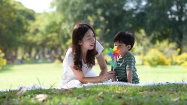 快乐的亚洲家庭，快乐的妈妈和儿子一起在花园里玩风车