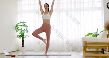穿着运动服的年轻女子在家里做<strong>瑜伽垫</strong>运动训练