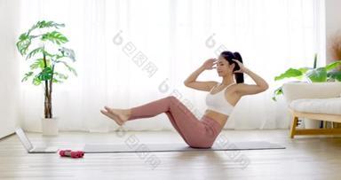 穿着运动服的年轻女子在家里做<strong>瑜伽垫</strong>运动训练