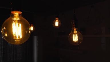 巨大的老式白炽灯泡挂在黑暗的厨房里.装饰古董爱迪生灯泡与直线线。低效率的灯管浪费电.温暖的白色调光器，导引