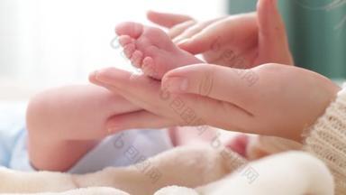 <strong>母亲</strong>触摸和抚摸新生婴儿小脚的特写镜头。家庭幸福和有年幼子女的慈爱父母的概念。婴儿按摩和保健