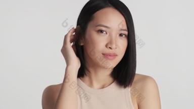在白色背景下,美丽的亚洲女孩在镜头前摆姿势的肖像.亚洲模特儿在演播室摆姿势