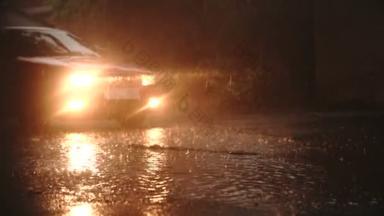 车底下着大雨.城市在雨天。站在城市街道湿湿的柏油上的汽车。地面上水坑里的倒影。慢动作