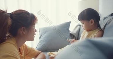 快乐快乐的亚洲家庭妈妈教女孩用相册和彩色铅笔在客厅的沙发上玩乐放松。在一起的时间，社会距离，验尸.