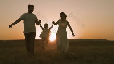 和爸爸妈妈在日落的时候跑过田野，快乐的家庭，和父母一起过着快乐的生活，和父母一起跑着去散步，积极的生活习惯，照看孩子，爱和关心孩子，团队合作