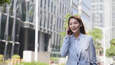 young asian businesswoman talking on phone while walking on street in modern city