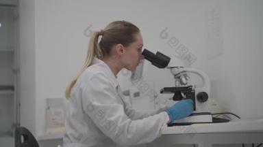 女科学家在实验室工作时使用显微镜.现代<strong>医学研究</strong>实验室。女性实验室助理在显微镜下观察样本生化物质、血液检测