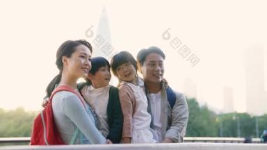 亚洲的一个年轻家庭，有两个孩子站在桥上，在公园的室外观看风景
