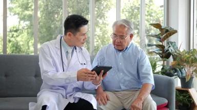 亚洲男性专业<strong>医生</strong>在家里坐在沙发上，用数字平板应用软件访问老年患者，解释处方，并给出了医学测试结果。老年人保健技术概念.