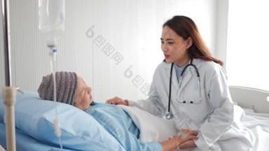 有爱心的亚洲医生在医院病床上看望老年妇女病人，友好的医生牵着病人的手与她交谈，感到好消息。老年人保健概念.