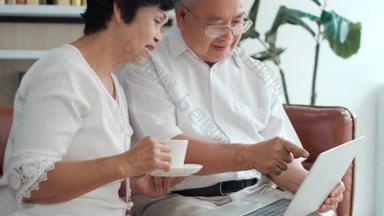 快乐的亚洲老年夫妇使用笔记本电脑一起上网购物，年长的退休家庭阅读讨论网络计算机新闻，选择在家里的网站上旅行.