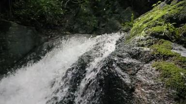 热带河流中的河流或湖泊瀑布运动缓慢，自然优美。野生山川清澈清澈的溪流.被石碑流淌的吱吱嘎吱的小溪射中.