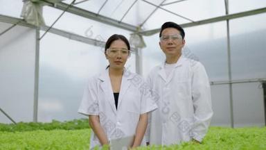 亚洲女<strong>科学家</strong>和亚洲男<strong>科学家</strong>共同研究温室实验中水栽植物的有机蔬菜实验结果.