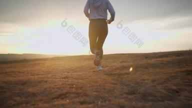 Closeup view of the strong woman running on a rural field at sunset during the summer. Healthy sport