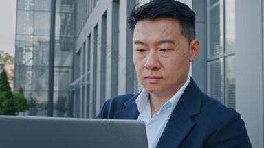关闭亚洲40多岁的商人企业家雇主男性员工经理老板设计金融分析师在城市室外从事电脑打字远程在线工作网络项目