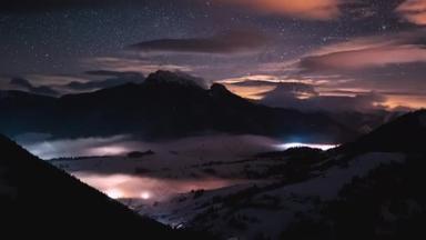 在雾蒙蒙的山谷自然景观中，夜空和星星的神奇光芒在冬季快速地摇曳着高山。天文时差，倾斜向上