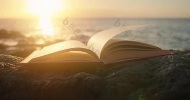 日落时带着光芒在海滩上<strong>翻开</strong>的书.背景上的海浪。智慧教育科学概念.