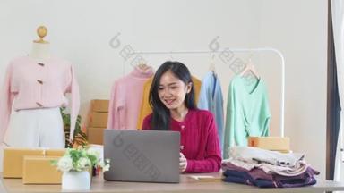 快乐的年轻女商人在家里用笔记本电脑接网上商店订单。在网站管理业务理念上与客户沟通的时尚零售店店主微笑.