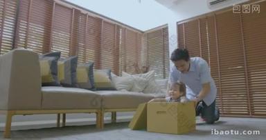 快乐的父亲和他的儿子一起玩纸板盒在家里一起