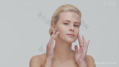 年轻、美丽、自然的金发女子应用<strong>护肤</strong>霜的工作室肖像。 面部整容、化妆品及化妆.
